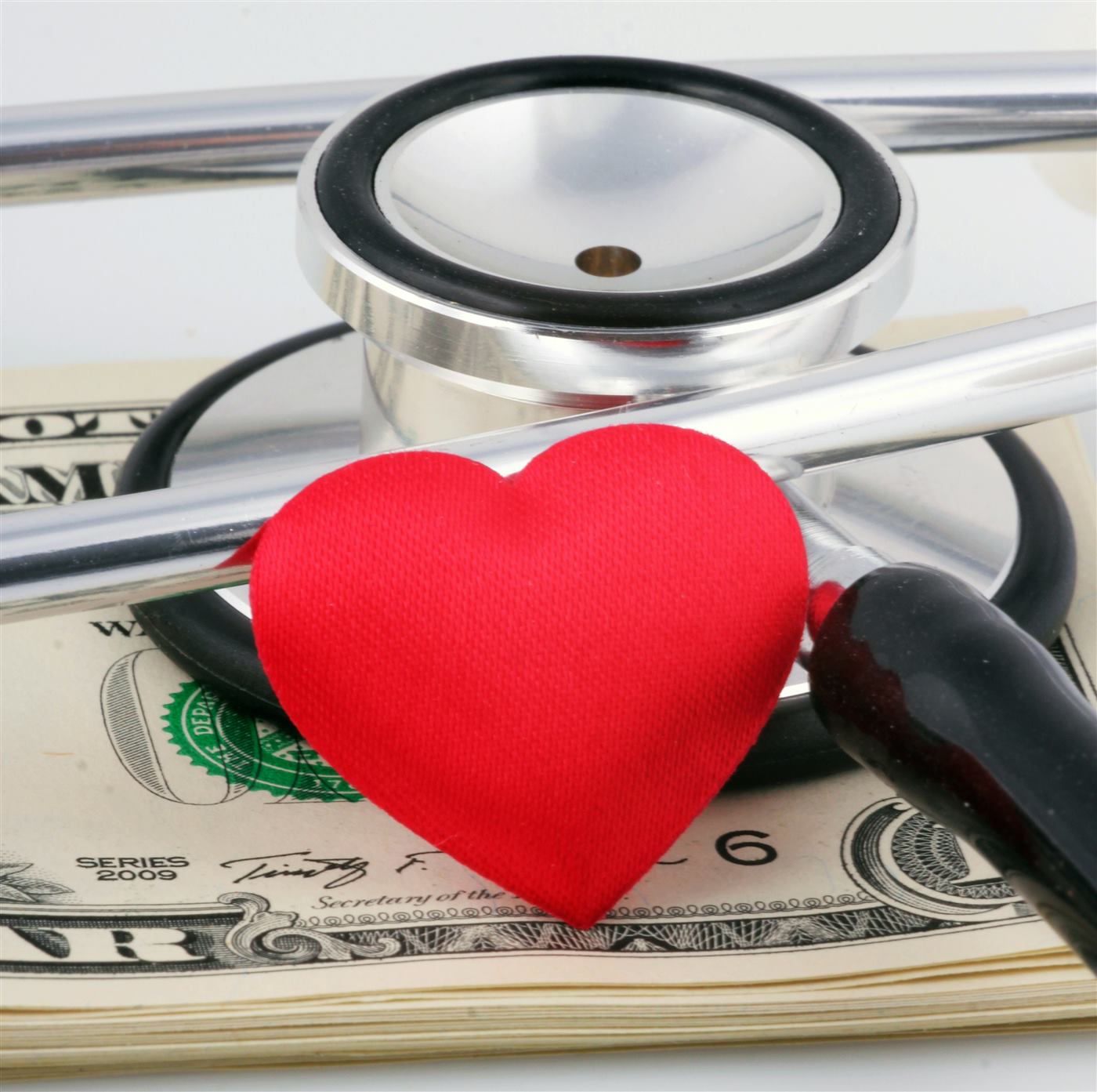 A stethoscope and a fabric heart resting on cash, symbolizing health and budget